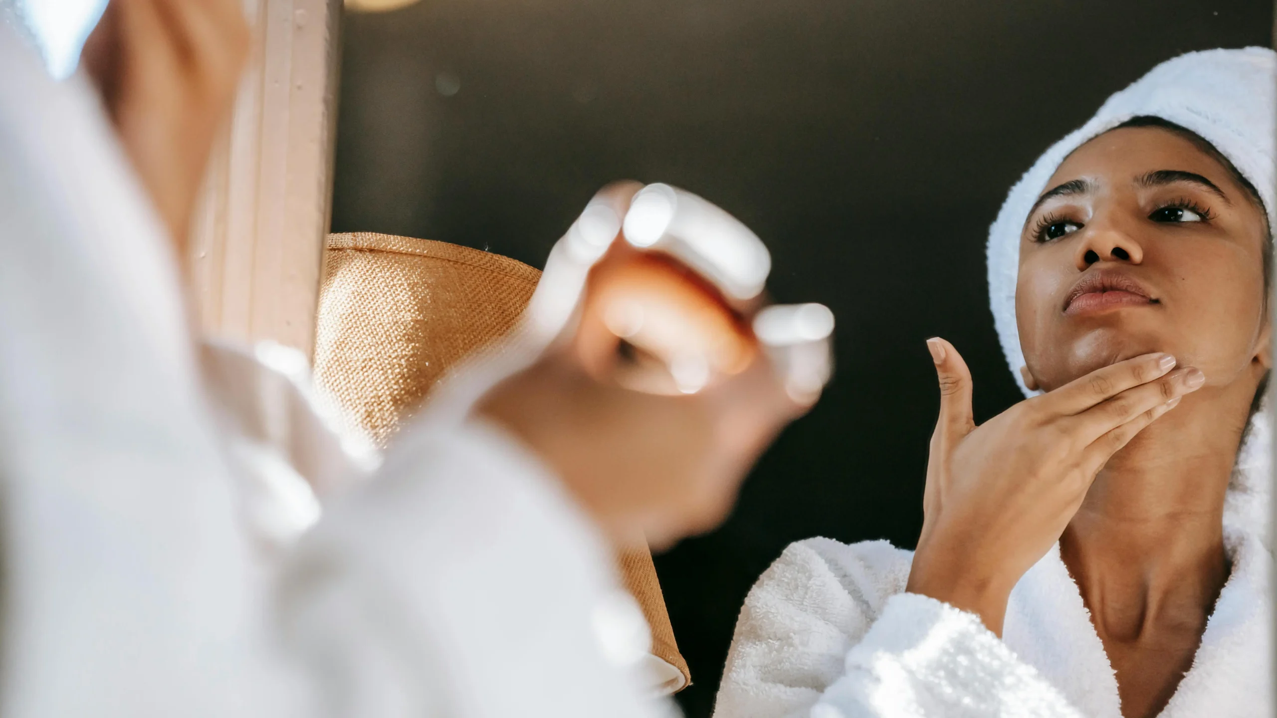 Woman in bathrobe applying cream, addressing breast sweat rash prevention in the bathroom