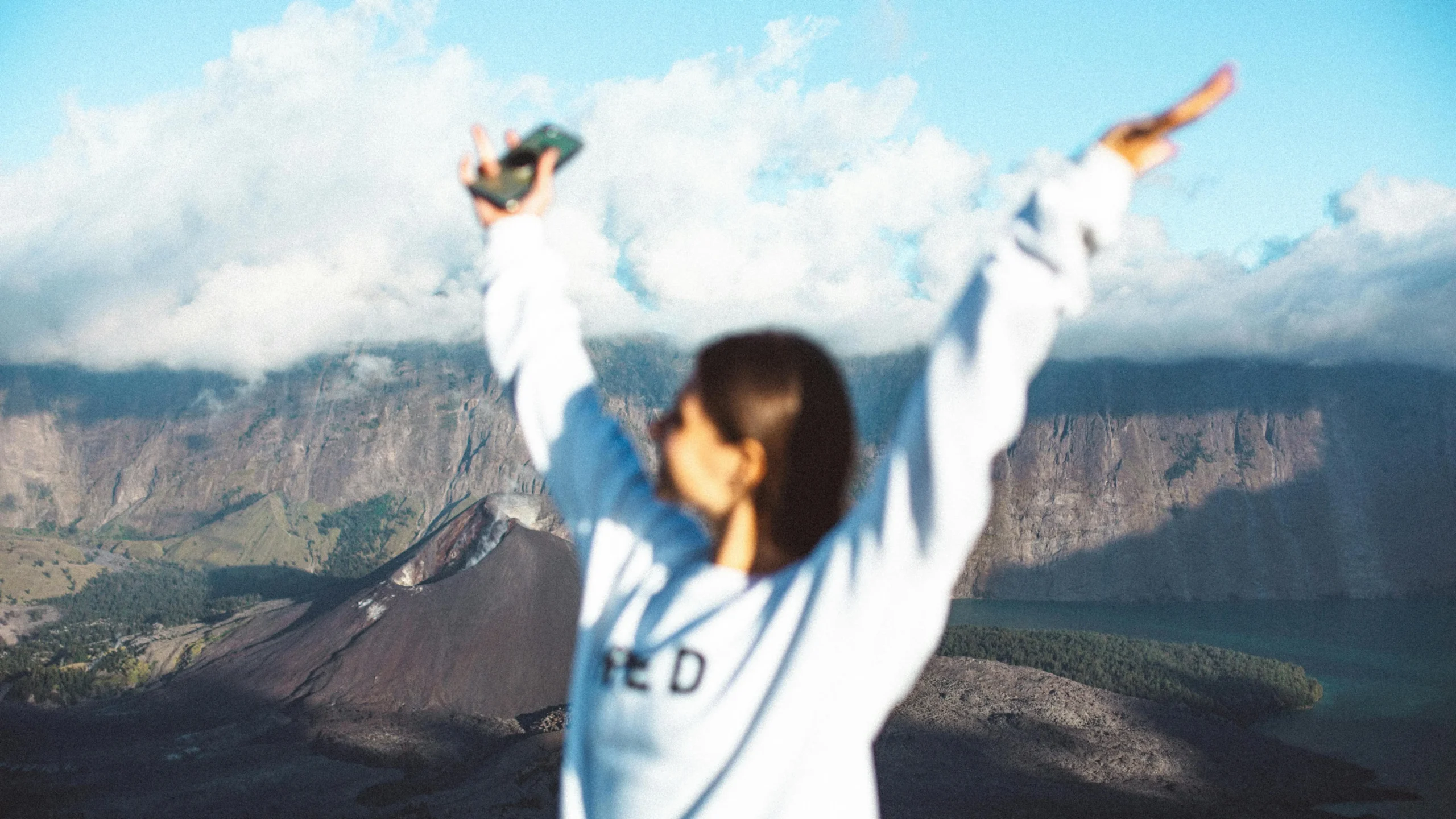 Young woman in white sweater near mountain, learning how to hide BV odor on her mobile phone