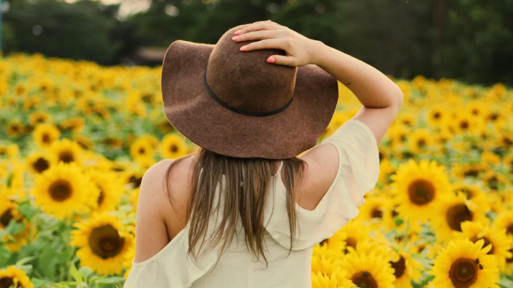 Woman in sunflower field reflecting on menopause vaginal odor.