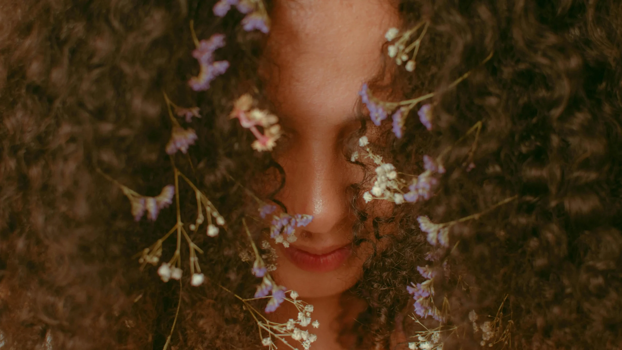 Anonymous woman with small white and purple flowers tangled in brown hair, representing a pubic ingrown hair cyst.