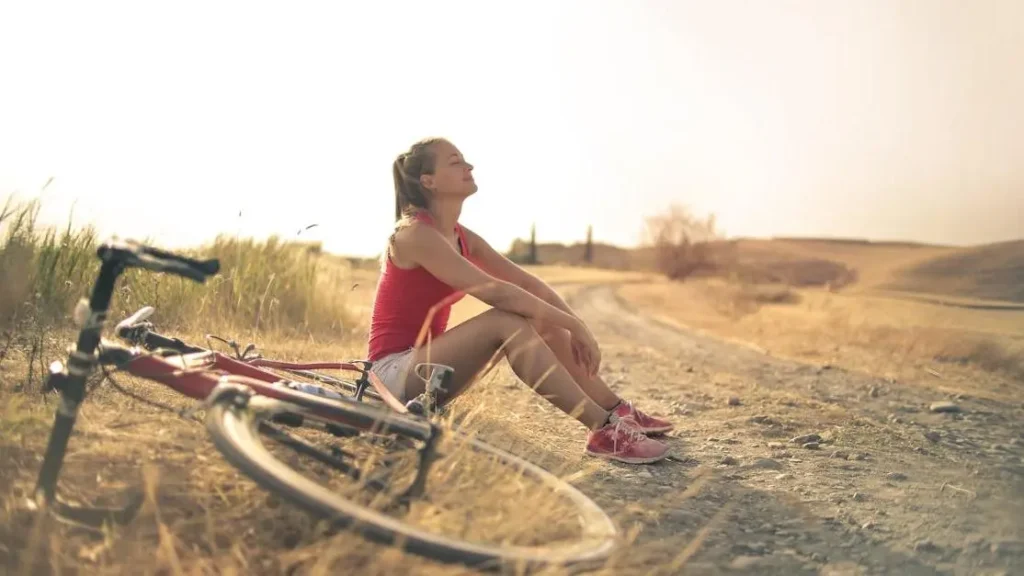 Woman in shorts and top enjoying fresh air by roadside with bicycle, best deodorant for vag odor.