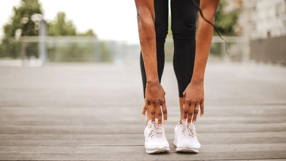 Athlete stretching forward to prevent chafing between thighs on urban sports ground.