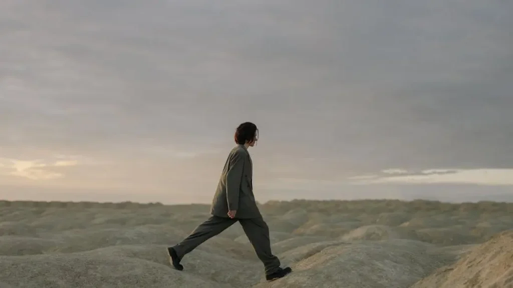 Man showcasing chub rub remedy by walking comfortably on beach in long sleeves and black pants