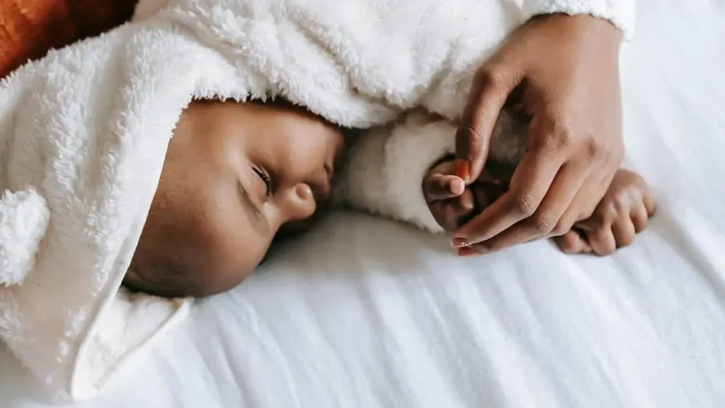 Mother embracing newborn baby in bed, highlighting postpartum dryness duration.