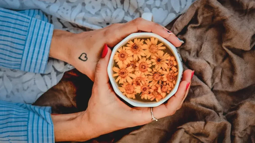 Woman warming hands on a hot beverage surrounded by flowers, illustrating menopause and sore breasts