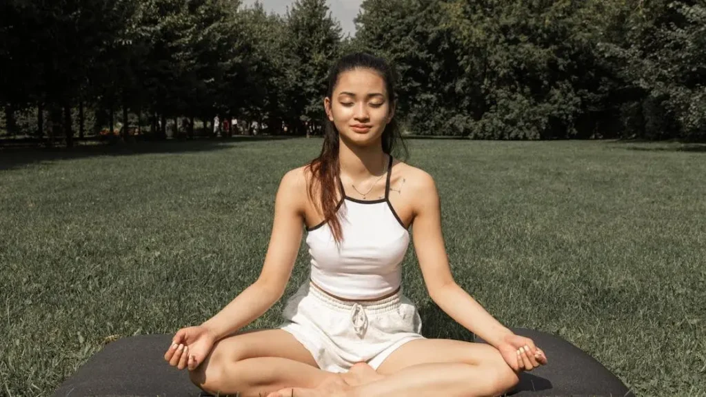 Woman doing lotus pose in nature, illustrating menopause tummy fitness tips