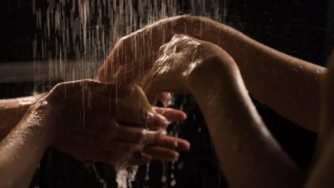 Person washing hands in the shower emphasizing hygiene in preventing Bacterial Vaginosis