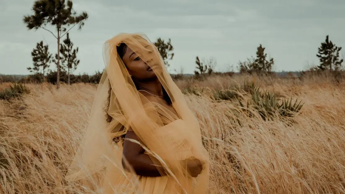 Woman in yellow veil standing in tall grass representing Black Cohosh for Hot Flashes