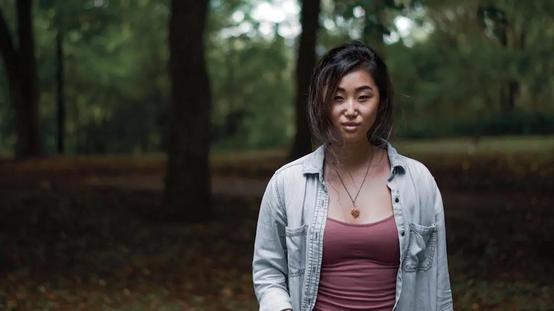 Woman in the woods with hands in pockets, discussing BV or yeast infection symptoms