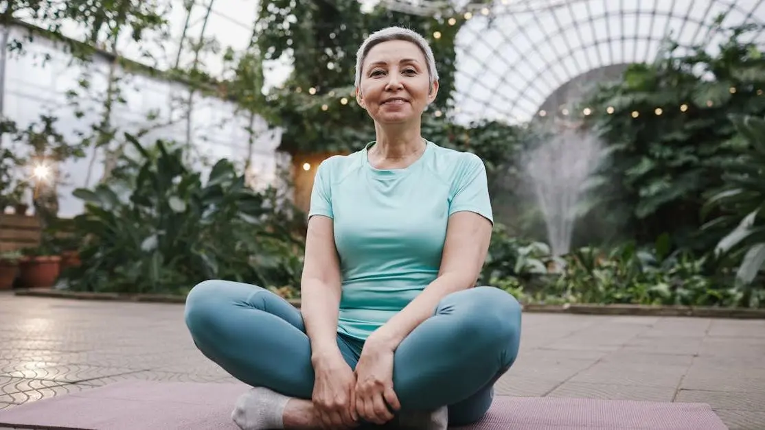 Smiling woman sitting on a yoga mat, promoting BV prevention in post-menopausal women.