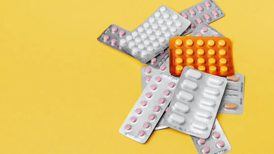 Various pills in blisters on yellow background for Combination Hormone Therapy and Hot Flashes.