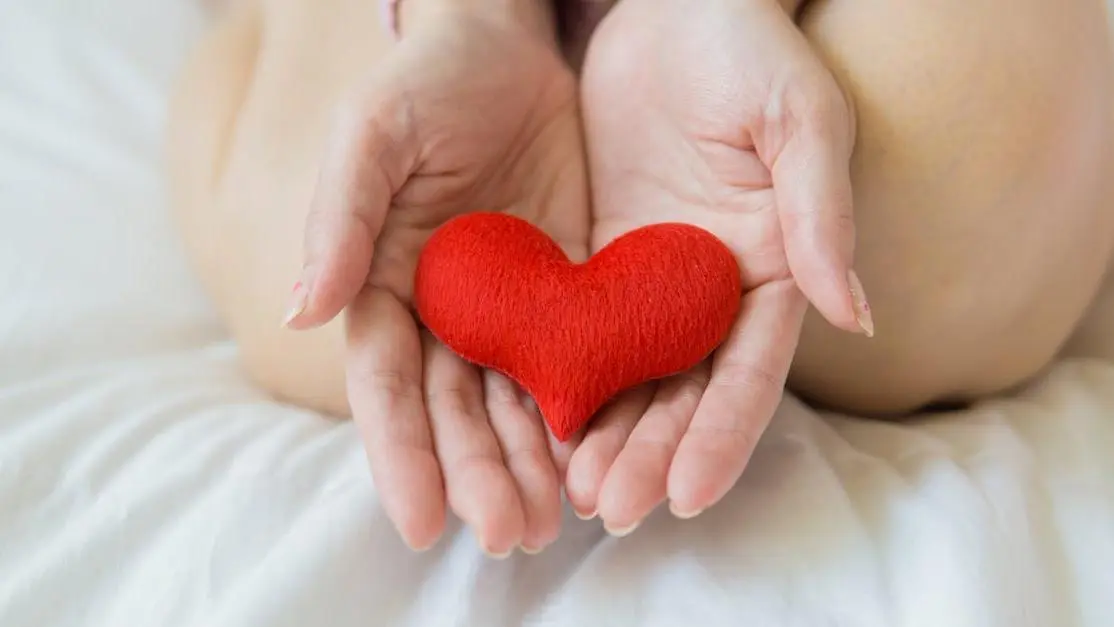 Woman holding heart on white sheet, illustrating Gabapentin for Hot Flashes.