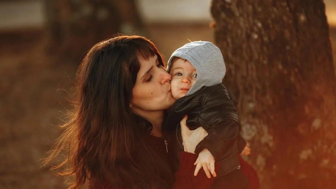 A woman experiencing hot flashes at 8 weeks pregnant while holding and kissing her baby