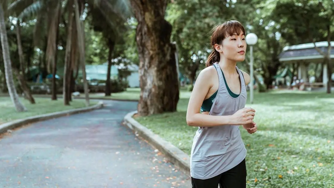 Asian woman jogging in park to manage hot flashes through exercise