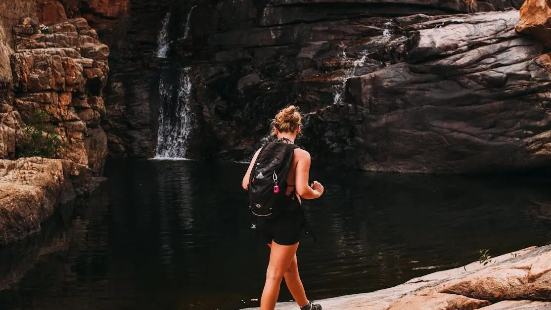 Woman experiencing hot flashes and menopause near scenic waterfall and river.