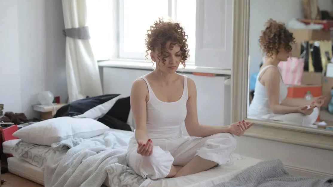 Woman in sleepwear practicing yoga on bed to manage Hot Flashes and Night Sweats