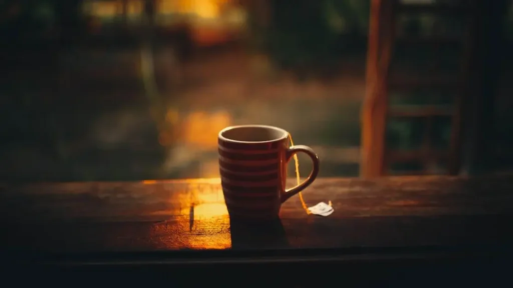 Morning hot flashes with tea on balcony railing against sunrise.