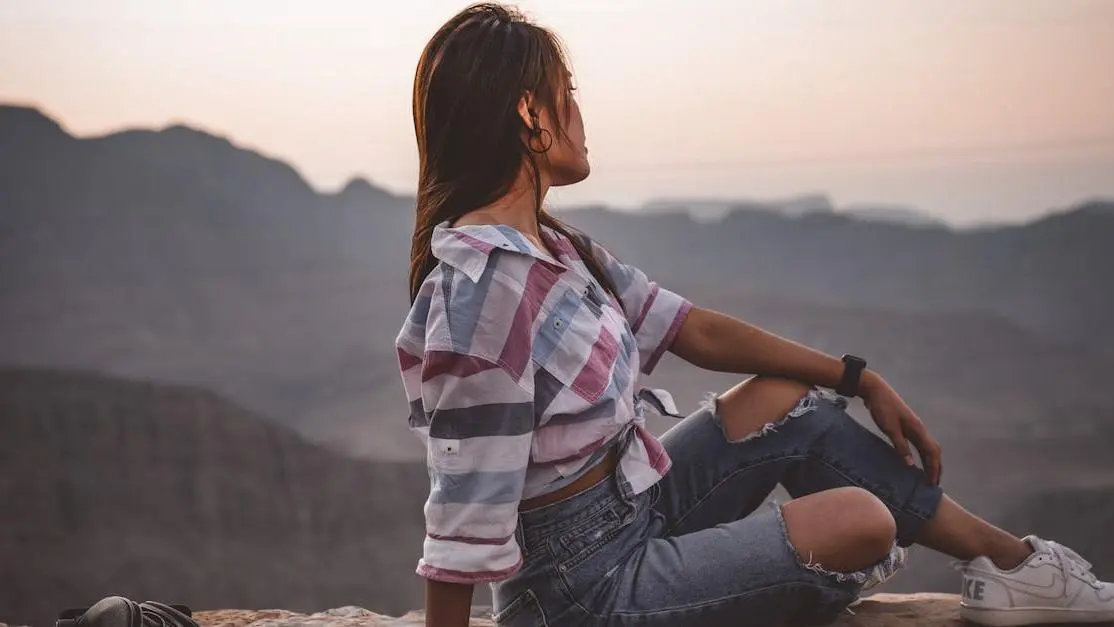 Woman on cliff at sunset, contemplating mountains, symbolizing HRT for Early Menopause journey