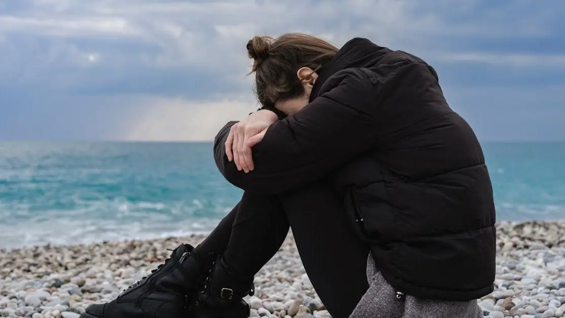 Woman experiencing irritability during menopause sitting on rocky shore