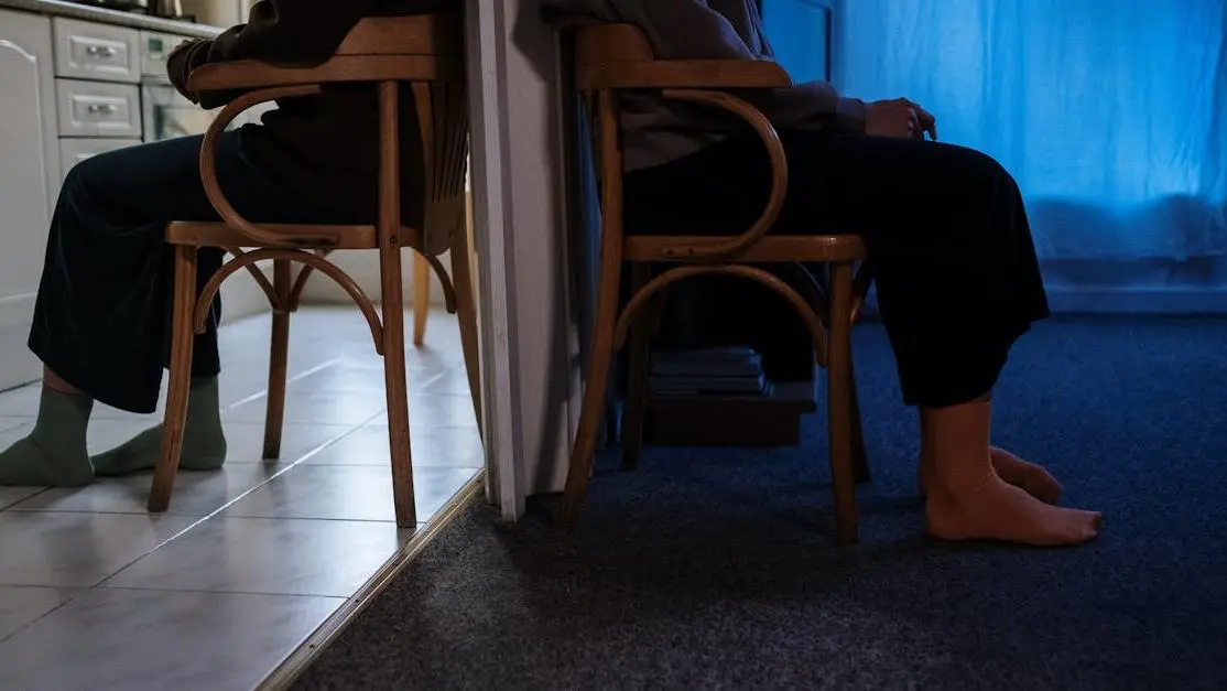 Woman experiencing irritable legs during menopause sitting on a wooden chair.