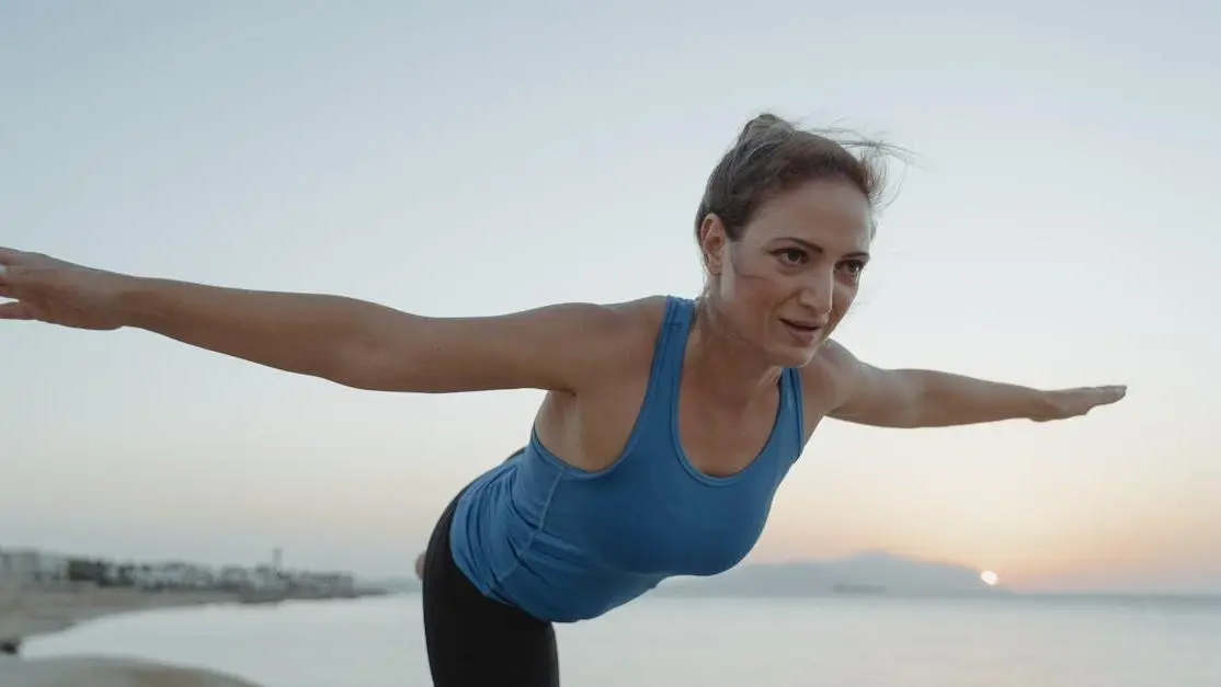 Woman practicing yoga by the shore at sunrise, symbolizing Menopause and Bone Health