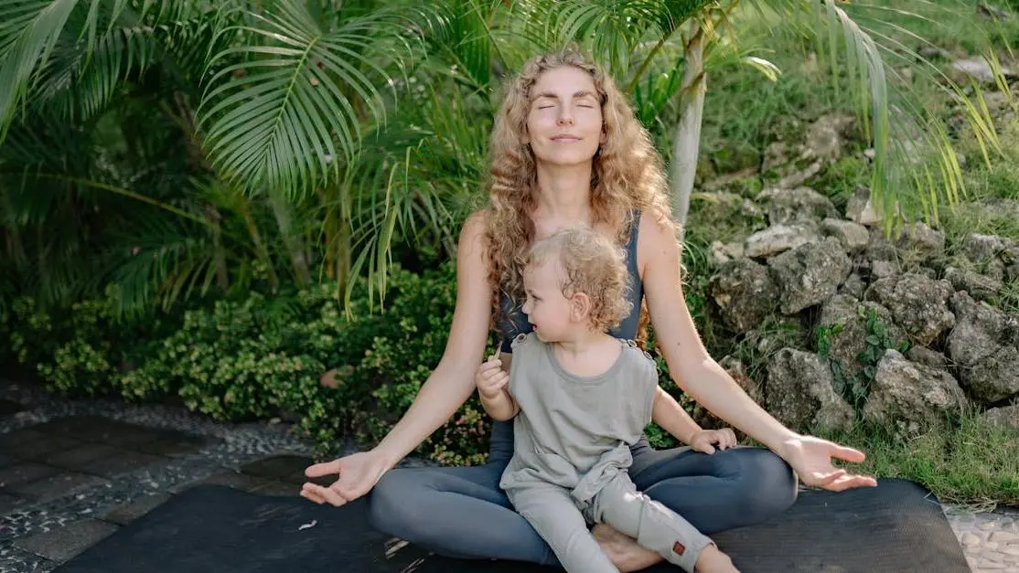 Happy mother practicing yoga in lotus pose with child in tropical park, Menopause and Weight Management