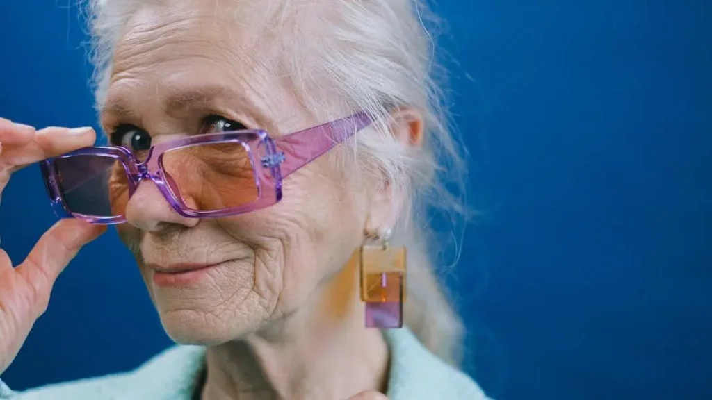 Smiling elderly woman in purple glasses debunking "Myth: Menopause Causes Depression"