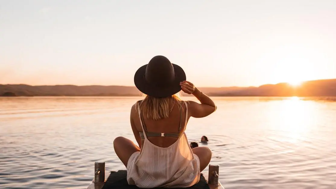 Woman in hat enjoying lake sunset, symbolizing natural help for menopause mood swings.