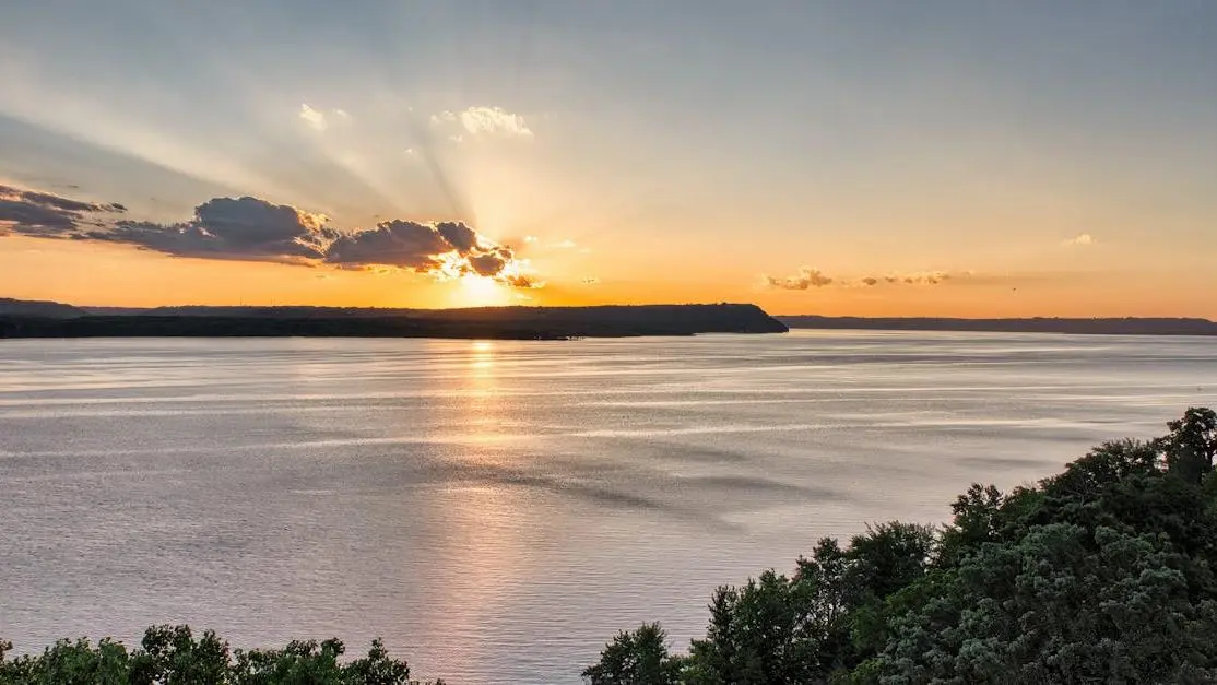 Sunset over water with trees and hills, illustrating tranquility in "Natural Remedies for Menopause Symptoms"