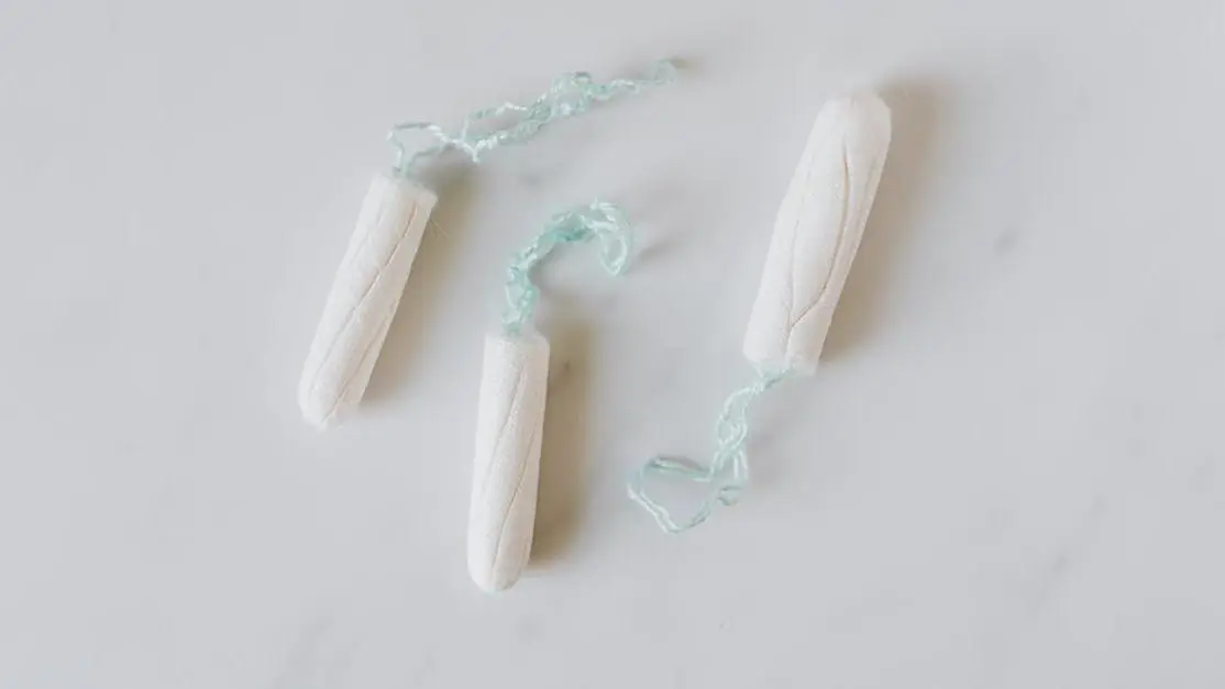 Three hygienic cotton tampons on a white marble surface. Preventing BV with Safe Menstrual Products.