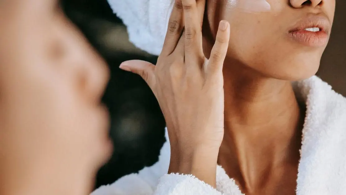 Young woman in terry robe applying cream, highlighting skin care routines during menopause