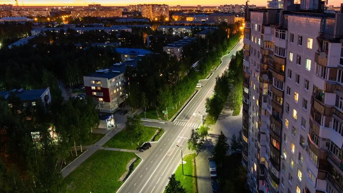 Sunset over city street with residential buildings, highlighting sleep disturbances in urban environments