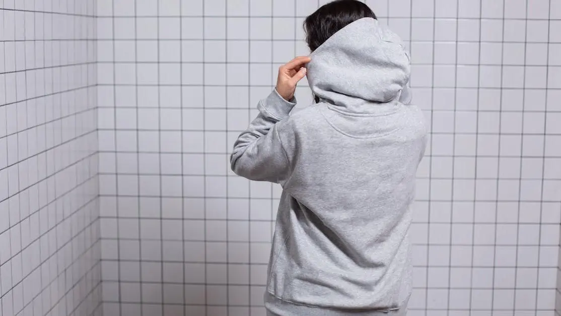 Woman adjusting sweatshirt hoodie, illustrating sweat rash from bra.