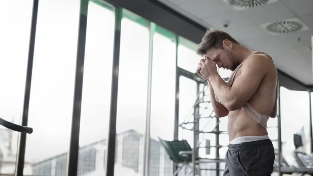 Tired muscular sportsman with sweat rash from working out in the gym