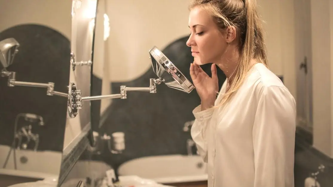 Woman examining skin in mirror for sweat rash symptoms