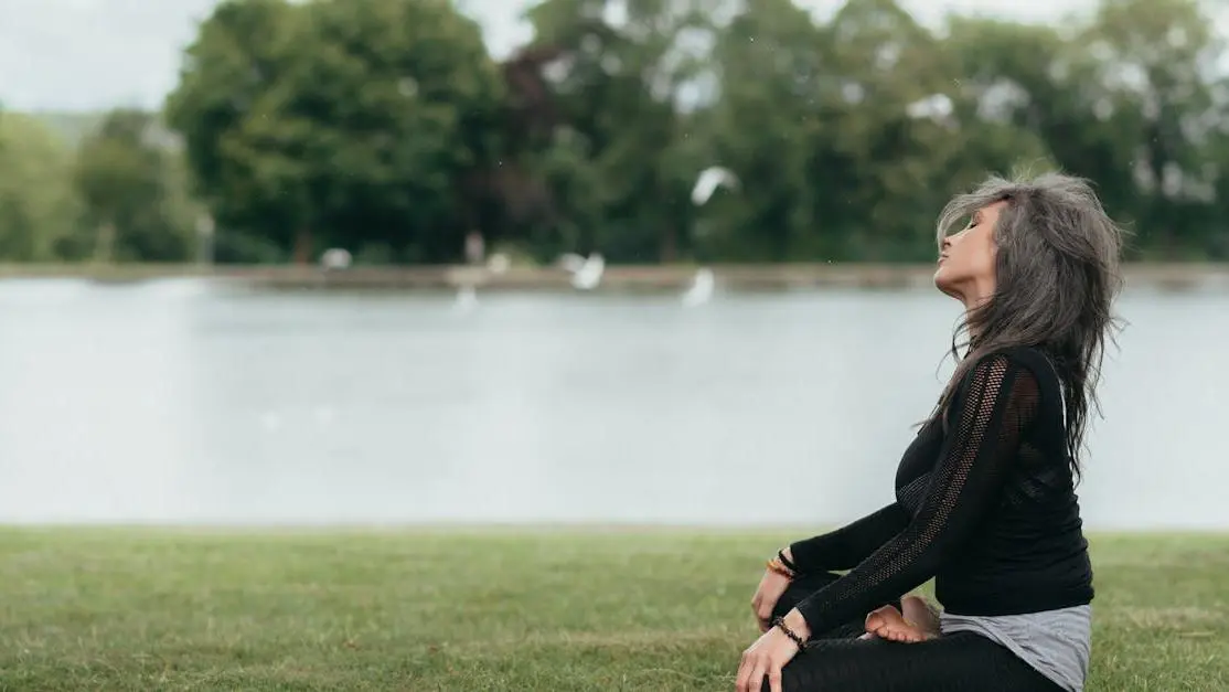 Mindful woman practicing meditation by river, exploring vitamins for hot flashes.