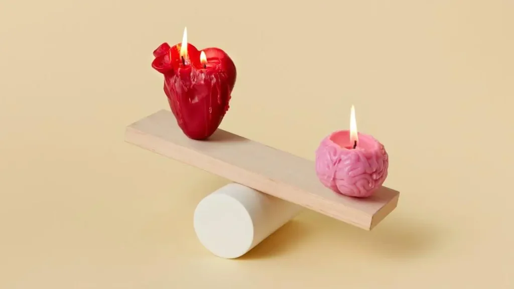 Heart-shaped and brain-shaped candles balancing on a seesaw, symbolizing side effects of Semaglutide.