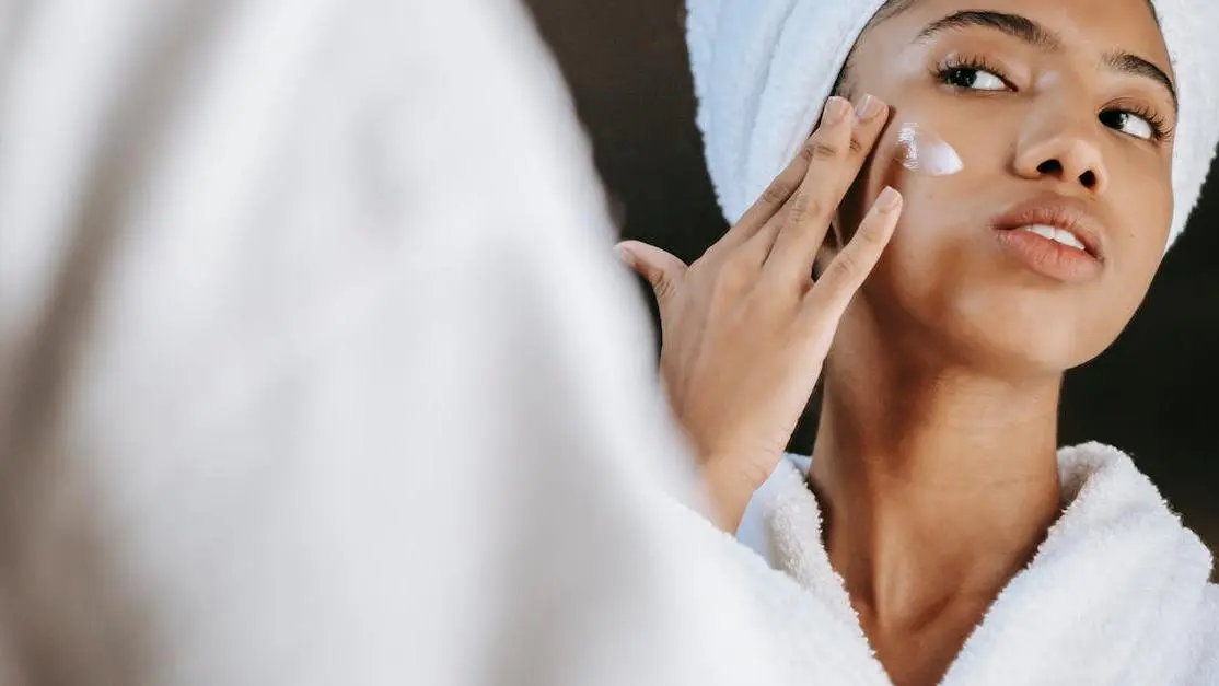 Skincare routine before red light therapy: woman applies moisturizing cream.